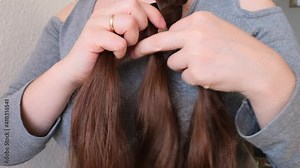 young woman, brunette, braids her long beautiful hair in a thick braid, concept of hygiene, hair care, traditions