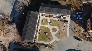 From high above, witness the seamless integration of sustainable technology into urban landscapes as the sun's rays dance across the sleek panels, generating clean energy for the community below.