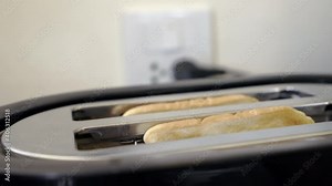 Close up toast popping out of toaster machine in kitchen, Roasted bread jump out of toaster making breakfast Concept cooking roasted food, Slow motion and handhelds.
