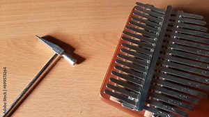 tuning the kalimba tone with a small hammer, thumb piano