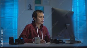 casual young Muslims Asian wearing red hoodie getting tired and sleepy when working from home at night in a modern interior design workspace with the warm blue light