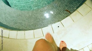 Point of view of a woman putting on her bikini and waling into the swimming pool.