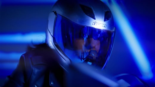 A futuristic motorcyclist wearing a helmet in blue light driving through the city - Free Stock Video