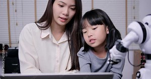 Teacher teaching little girl about progarming robot by computer. Girl having training class to develop hardware with teacher.