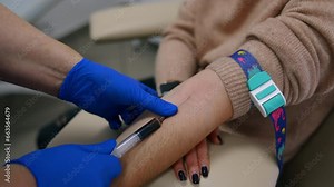Medic's hands in blue latex gloves fill the syringe with blood. Test sample taking from vein on arm. Close up.