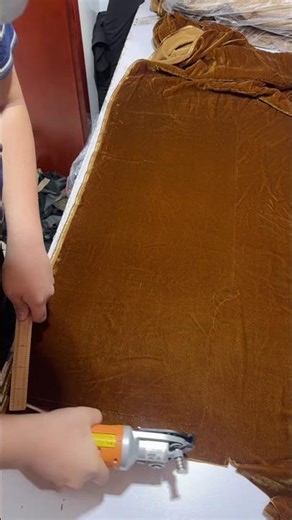 Handheld electric rotary fabric cutter to cut multiple layers of a mustard-brown micro velvet fabric