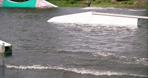 Wakeboarder doing tricks at cable wake park 4k wakeboarding video. Water extreme sport. Man jumps and rotates