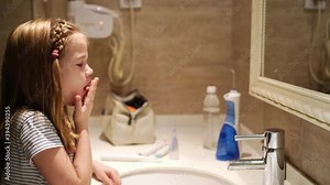 girl brushes teeth in bathroom with an electric toothbrush. daily oral hygiene.