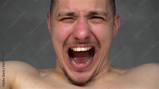 A man crying and screaming in front of the camera. The actor screams while looking at the camera.