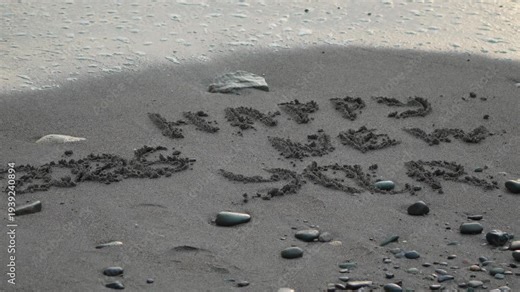 Sand writing new year. "Happy New Year 2026" message written on dark beach sand washed by calm ocean waves.