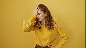 Oops! beautiful young woman realizes her blunder, reacting in despair with hand on head. forgotten error triggers stress memory. isolated yellow wall frames regretful portrait.