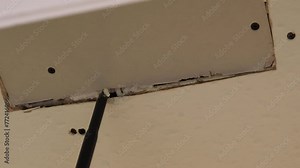 Man filling gaps with expanding foam after patching fixing hole in the plasterboard or drywall ceiling; handheld shot.