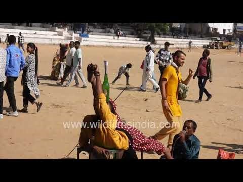At the vibrant Pushkar Fair a young woman performs a traditional circus act on an open fairground