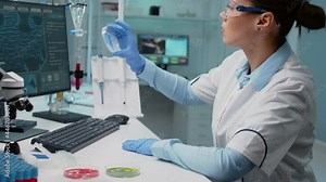 Scientist in laboratory analyzing petri dish with liquid bacteria while typing on computer with dna animation. Chemistry doctor with lab equipment working on genetic microbiology