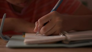 Download Close-up of the hand of a little girl writing on a notebook. for free