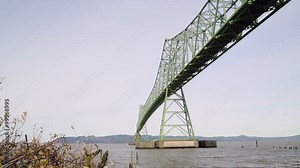 Astoria-Megler Bridge, Oregon. Dolly shot along the Columbia River shoreline on the edge of downtown Astoria. The Astoria Megler bridge between Oregon and Washington stretches overhead. Stock Video