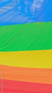 Big rainbow flag waving in slow motion during LGBT pride. Pride community celebrating love and diversity carrying big flag during lesbian gay bisexual and transgender march. Abstract background