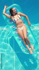 Sunbathing and tanning in a swimming pool - top down view - Vertical video