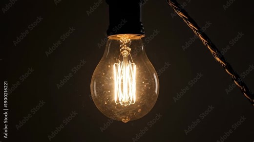 Flickering light bulb. A single light bulb hanging in a dark space, flickering intermittently and casting brief flashes of light.