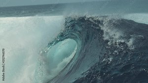 SLOW MOTION, CLOSE UP: Big splashing barrel wave rushes towards the coast of an exotic island in the sunny Pacific. Glassy droplets of water shine in the summer sun as big tube wave crashes wildly.