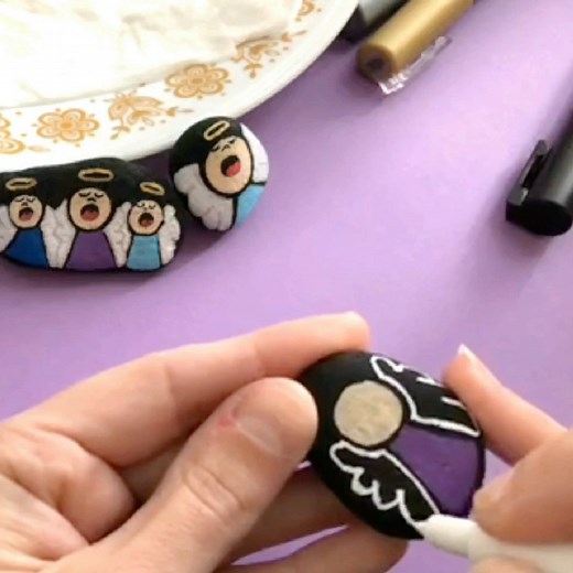 I painted these cute singing angel stones for the first time back in 2017!!! WOW! Anyways... l used a combination of my Posca extra fine tips, fine tips, and gold/silver to make them. Base coated the rocks with black acrylic paint. Comment "shop" if you need supplies! Check out more from our Winter - Holiday - Christmas Rock Painting Ideas - https://www.facebook.com/1511584975583999/playlists/2338745503245426 | Rock Painting 101