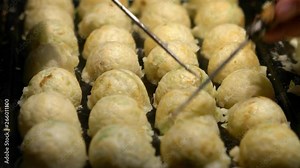 Japanese vendor prepare a Takoyaki on hot pan food Japan. Process to cooking the popular fried balls with octopus in local street food. Making a Ball-shaped food at asia night market.-Dan