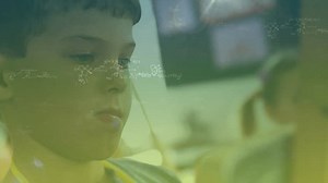 Mathematical equations floating against close up of a caucasian boy painting at elementary school. school and education concept