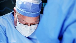 Surgical healthcare senior male surgeon with training team in scrubs working in modern hospital operating theater facility performing Orthopaedic surgery on patient RED DRAGON