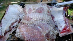 Injecting salt solution into hams made of pork shoulder and placed in sacks or meat netting before smoking.