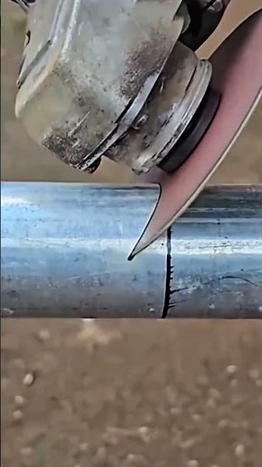 Cutting round steel metal pipes with a powerful electric angle grinder tool in a construction worksh