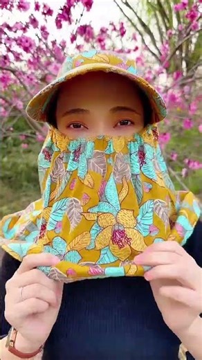 Stylish person wearing colorful floral sun hat and face cover, standing among blooming#springvibes