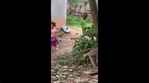 Girl catches a chicken and playfully tours it around in Aceh, Indonesia