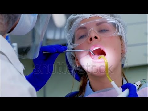 Beautiful girl receives teeth cleaning by female dentist