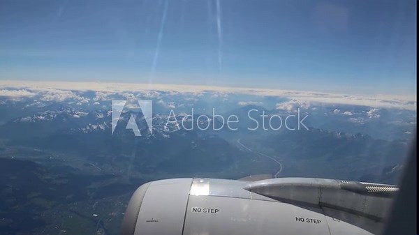 airplane flying through clouds over the alps in europe (pov point of view scene outside plane window) engine fly mountains hills haze sunshine cloud cover scenic travel tourism summer destination