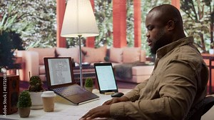 Businessman searching for commercial office spaces from his home workstation, doing a blueprints review and drafting building layouts to find the perfect startup property. Real estate. Camera B.