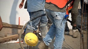 Slow motion of fresh concrete mix being pumped onto grid at a construction site in Mexico to create the house slab while workers use a concrete vibration machine