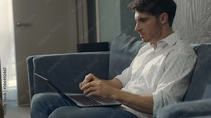 Angry guy hitting laptop indoors. Wicked man working on computer in hotel room.