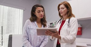Mid aged medical doctor using portable tablet to review test results of patient