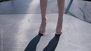 Close up view on children's feet bouncing on a trampoline. Slow motion full HD video of Children's legs are bouncing on the trampoline.