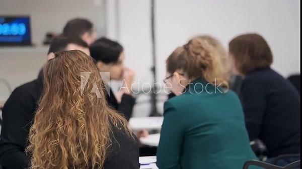 Group of professionals in meeting room discuss notes and ideas at round table