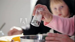 Making pancakes. An old woman salting the dough. A little girl watching her