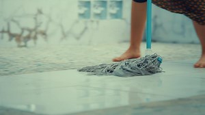 Barefoot person mopping a tiled floor