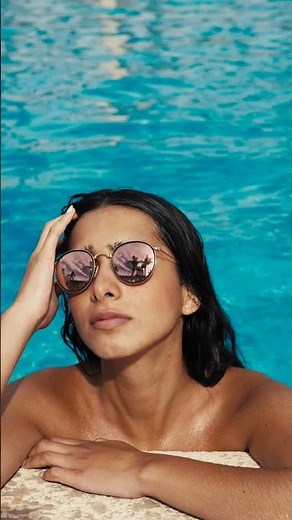 Footage woman with black hair wearing sunglasses in a blue outdoor pool girl getting a tan in summer