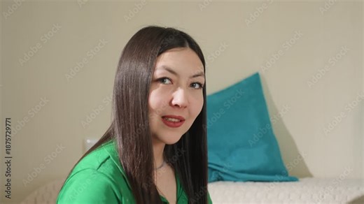 woman chatting comfortably on camera, casual female vlogger engaging directly from her bedroom space, an informal recording of asian woman speaking naturally into camera in her bedroom