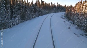 POV from the front of a train passing through a snowy landscape.