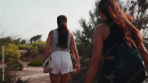 Two young women hiking on a nature trail during sunset