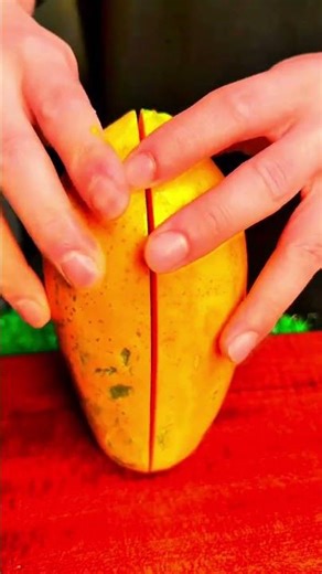 Slicing a fresh orange papaya with a sharp knife on a red board for food preparation