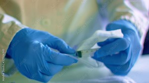 Doctor opens sterile syringe packaging for medical injection