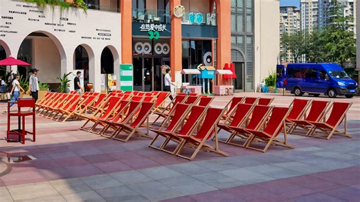 Urban gathering space with red chairs near cafes and shops