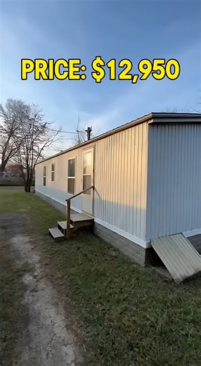 used mobile home listed at $12,950 From the outside, the home appears simple, with straight siding and level placement, though a small trim section near the skirting needs fixing. Inside, the layout feels practical rather than cramped, especially in the living area. The kitchen is centrally placed with older cabinets that still function properly. Toward the back, the bedroom offers clean walls and solid flooring, making it usable without major work. The bathroom is fully operational, although th